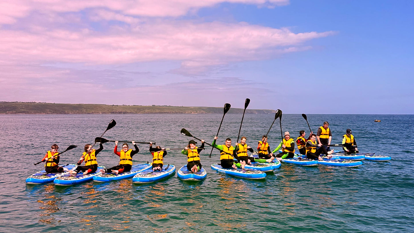 Large group of all ages sat on paddle boards on the sea